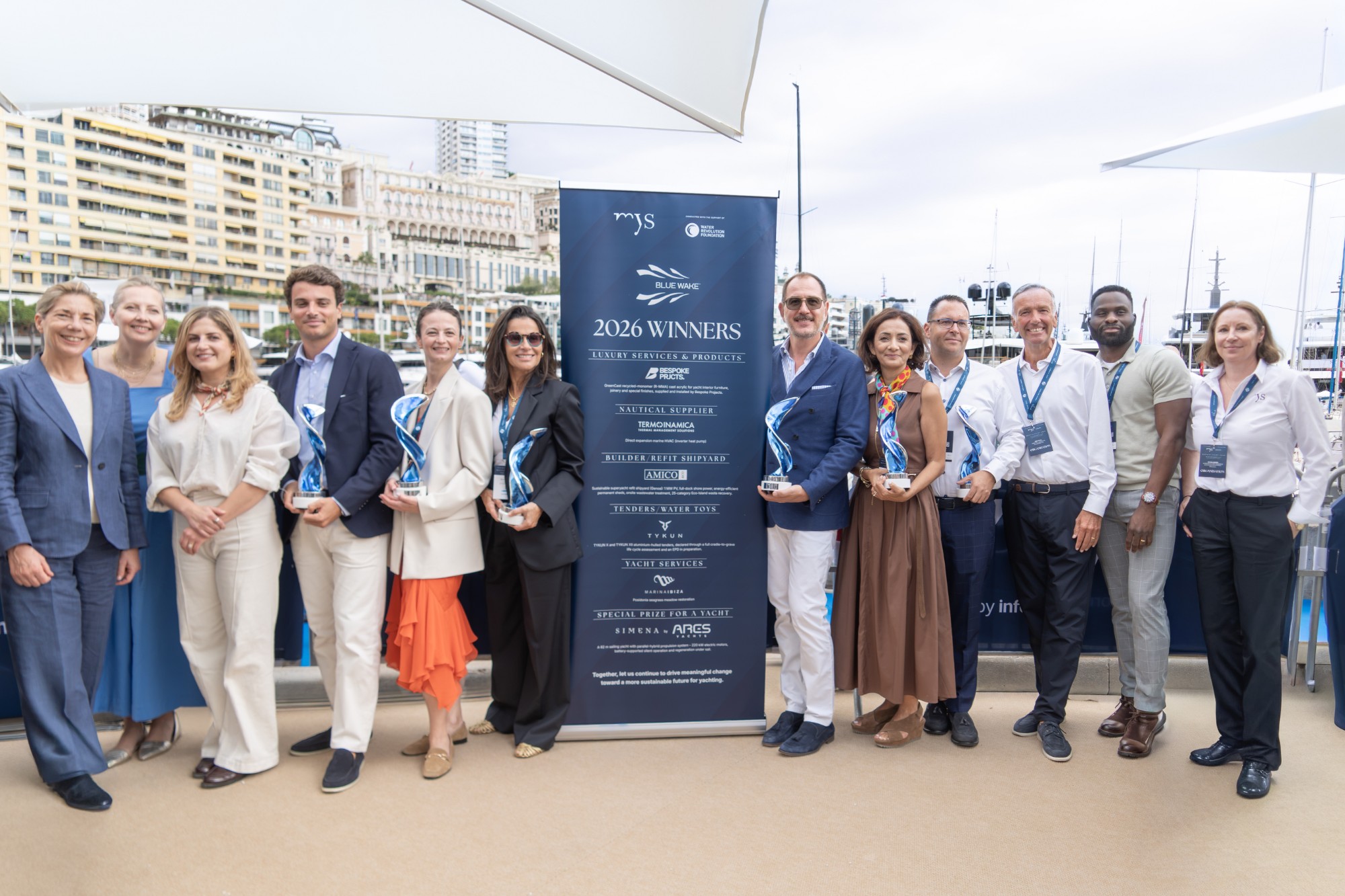 Ganadores de los Blue Wake™ Awards 2026 en el Monaco Yacht Show, con sus trofeos junto al cartel de premiados